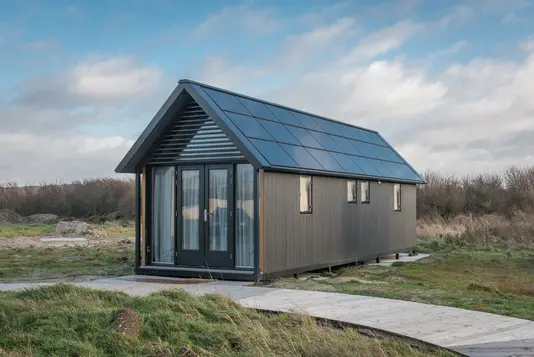 Singlehaus und Tiny House im Vergleich Ein modernes Singlehaus als feststehende Wohnlösung im Vergleich zum mobilen Tiny House, das Flexibilität beim Wohnort bietet.